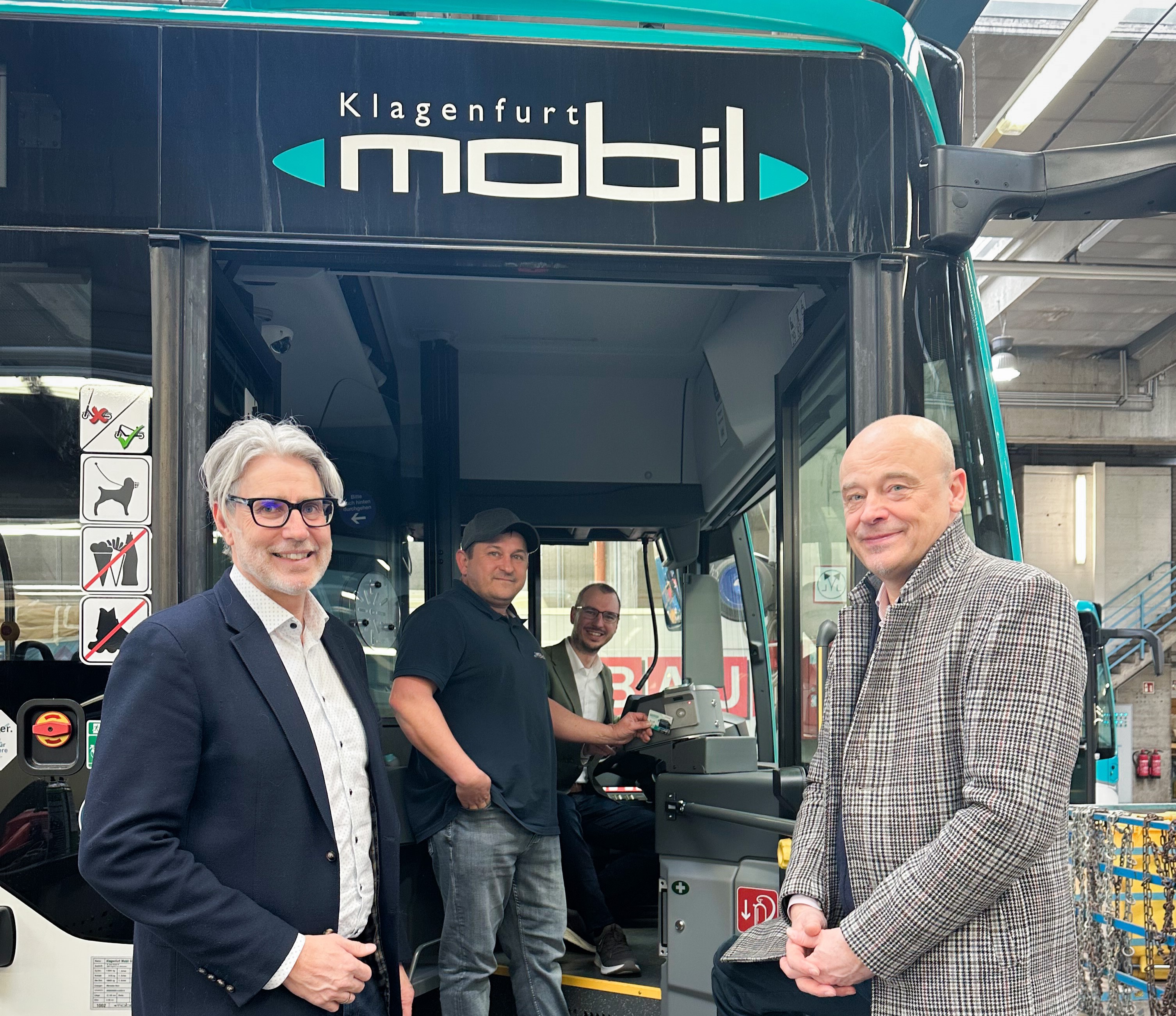 Two men standing in front of city bus with Klagenfurt mobil lettering