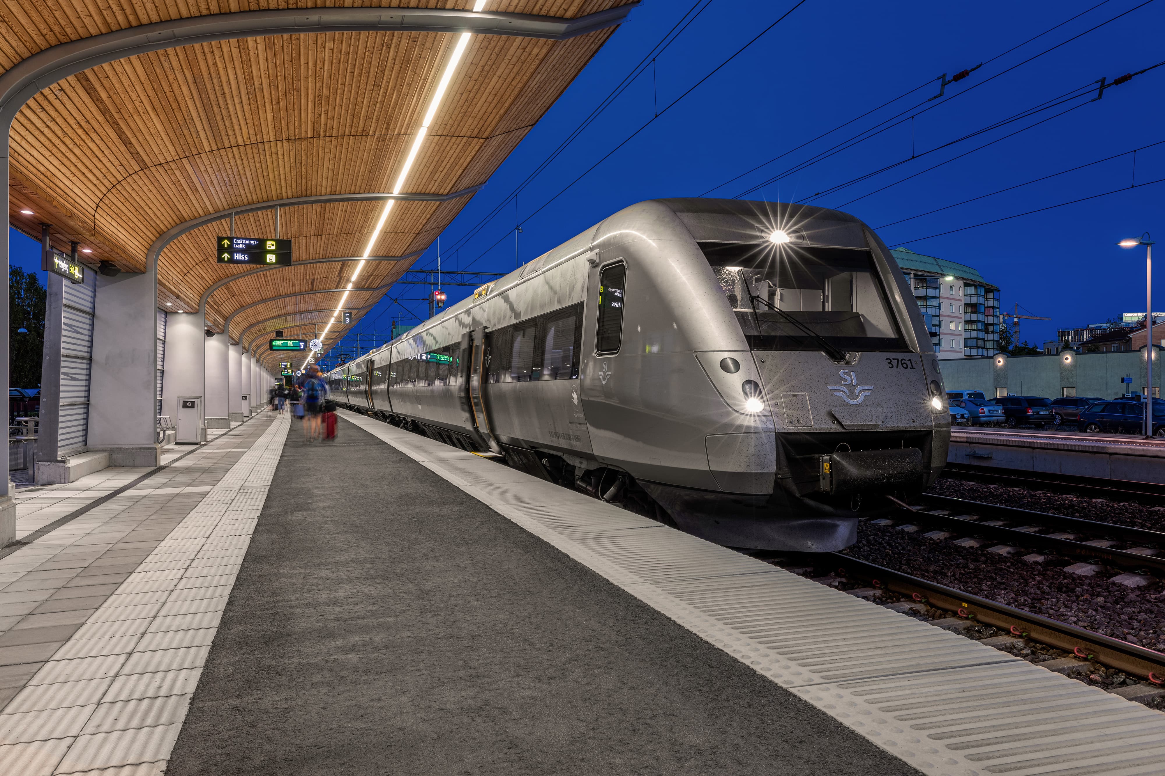 Modern railcar at illuminated platform under curved station roof at night