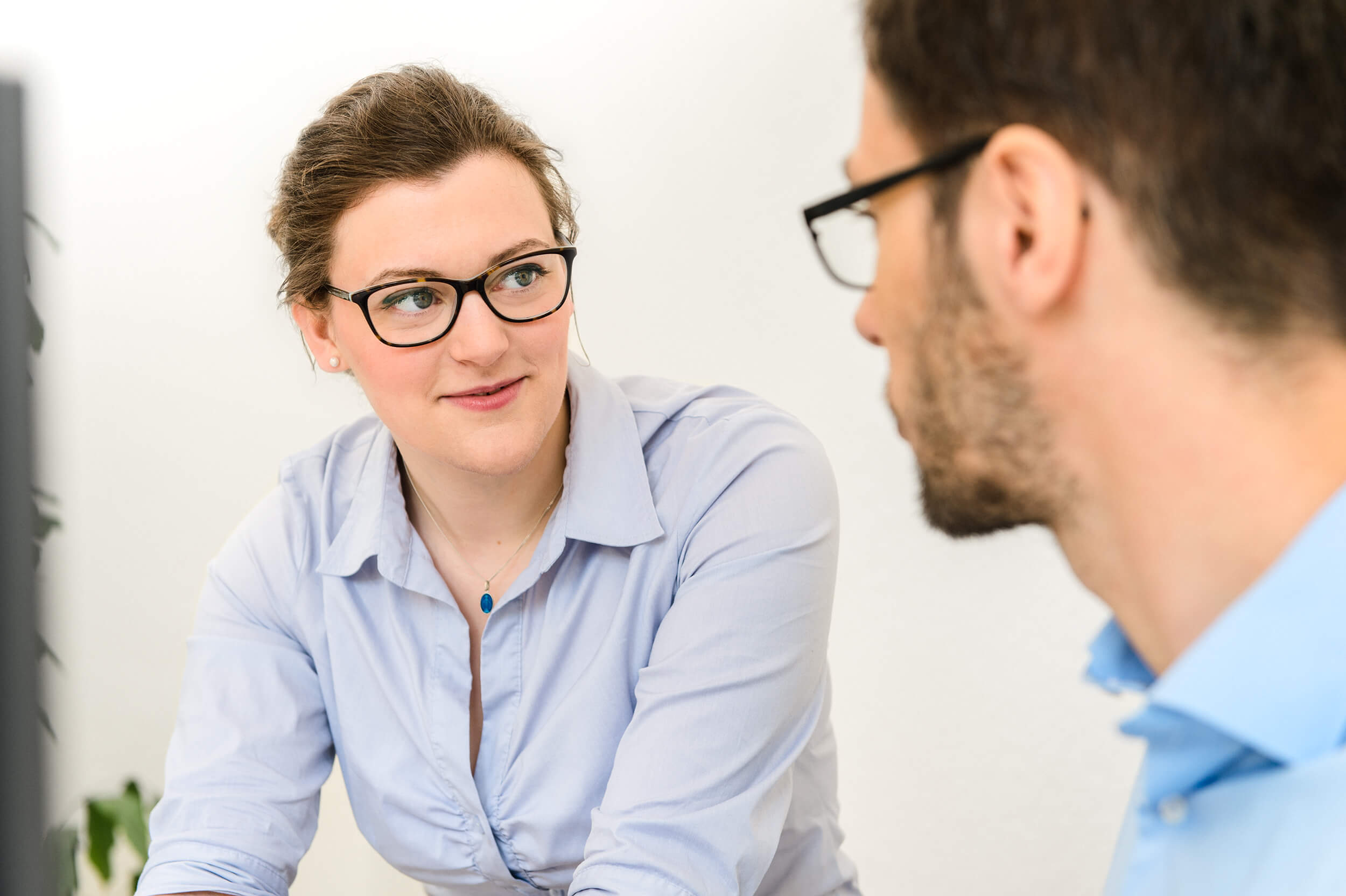 Two professionals in a face-to-face conversation, woman with glasses listening attentively