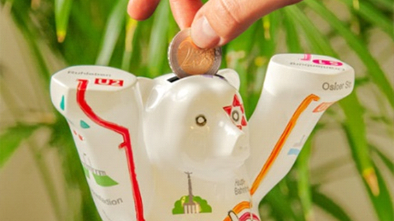 Hand putting a two-euro piece into a Berlin Bear money box